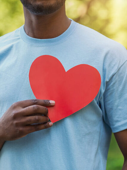 Black man holding red heart on his chest