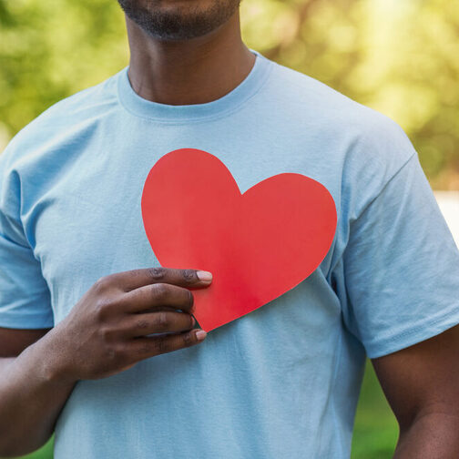 Black man holding red heart on his chest