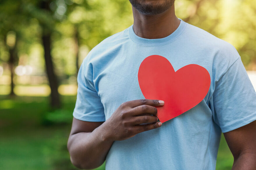 Black man holding red heart on his chest