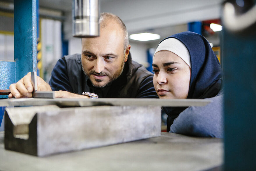 Techniker erklärt einer weiblichen Auszubildenden in einem Metallverarbeitungsunternehmen die Hydraulik