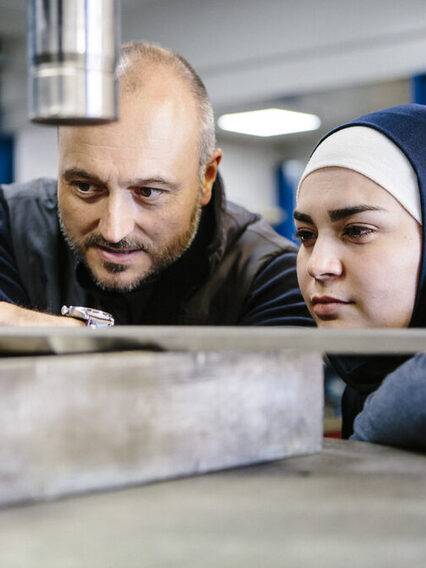 Techniker erklärt einer weiblichen Auszubildenden in einem Metallverarbeitungsunternehmen die Hydraulik