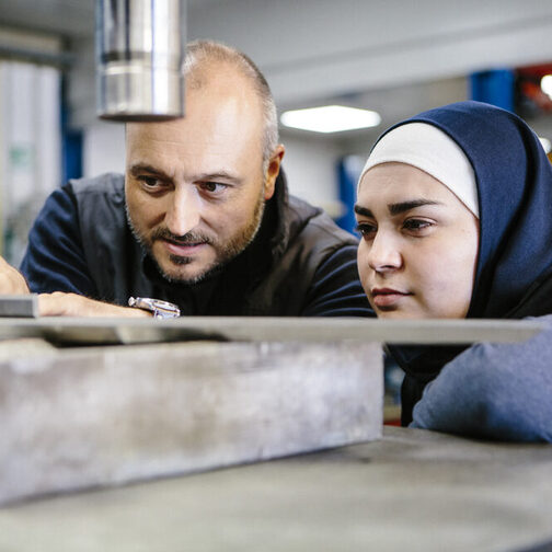 Techniker erklärt einer weiblichen Auszubildenden in einem Metallverarbeitungsunternehmen die Hydraulik